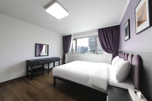a bedroom with a bed and a desk and a window at Hotel Hyggelig in Busan
