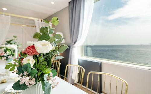 a vase of flowers on a table with a window at Hotel Hyggelig in Busan