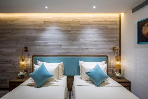 two beds in a hotel room with two blue pillows at Icon Saigon - LifeStyle Design Hotel in Ho Chi Minh City