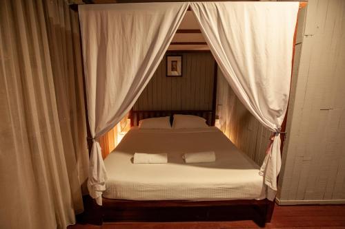 a bedroom with a canopy bed with white sheets at Joe Fisherman Inn in Pangkor