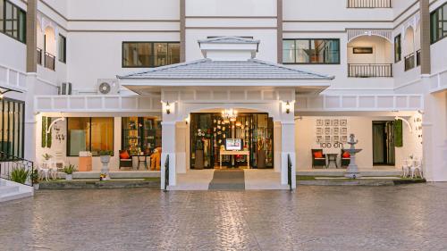 a large white building with a entrance to a store at De Hug Hotel & Residence in Chiang Rai