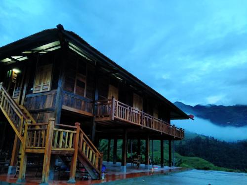une grande maison en bois avec une terrasse sur l'eau dans l'établissement Mù Cang Chải Dream House, à Lao San Chay