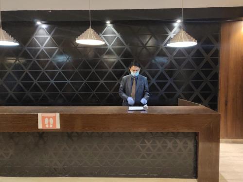 a man in a mask standing at a desk at Hotel Polo Towers Shillong in Shillong