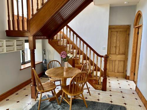 a dining room with a table and chairs and a staircase at Flatts farm, Yorkshire dales home in Skipton