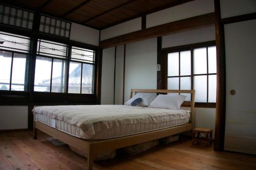 a bedroom with a bed in a room with windows at Munetada House in Kyoto