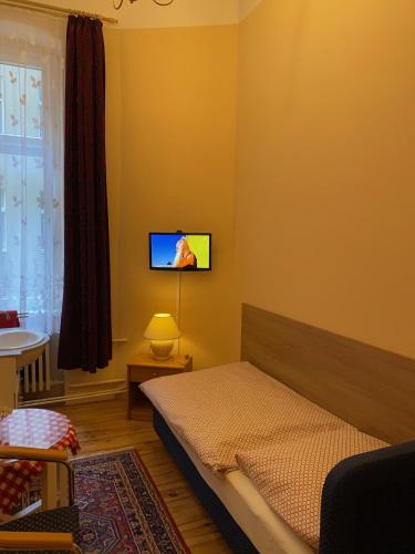 a bedroom with a bed and a tv on the wall at Hotel Gunia in Berlin
