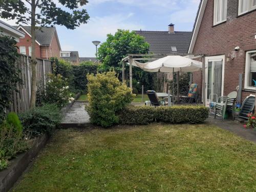 a backyard with an umbrella and a table and chairs at Logies bij Wandelpad te Holten in Holten