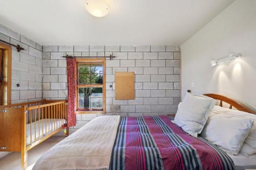 a bedroom with a bed and a window at Chalet Mahuta - Five Mile Bay Holiday Home in Waitahanui