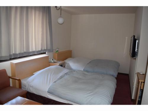 a hotel room with two beds and a television at Amami Port Tower Hotel in Amami