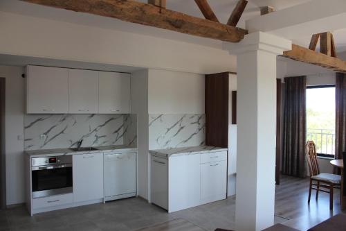 a kitchen with white cabinets and marble counter tops at Weißer Schwan Белият лебед in Shkorpilovtsi