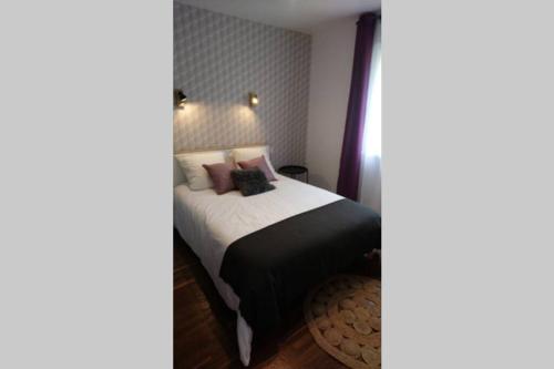 - une chambre avec un lit doté de draps noirs et d'oreillers roses dans l'établissement Ma maison de vacances en Bretagne, à Meillac
