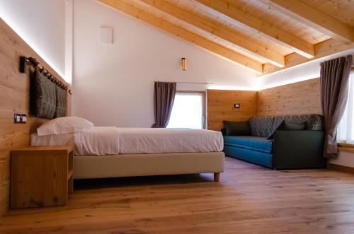 um quarto com uma cama e um sofá num quarto em Bioagritur La Casa dei Trajeri em Fai della Paganella