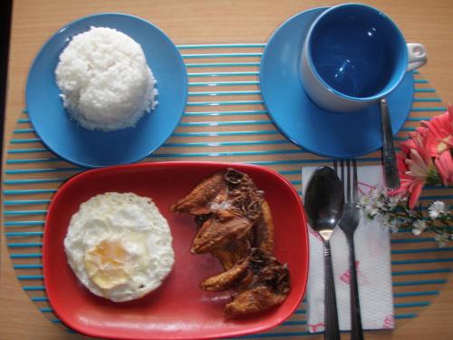 a plate of food with eggs and bacon and a cup of coffee at Anthurium Inn in Mactan