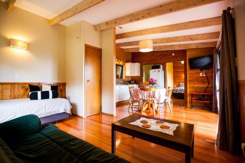 a bedroom with a bed and a living room with a table at Relax a Lodge in Kerikeri