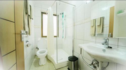 a white bathroom with a toilet and a sink at Hotel Africana in Kampala