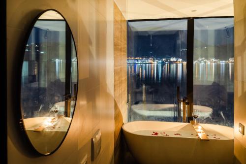 a bathroom with a mirror and a tub and a window at Rea Boutique Hotel in Himare