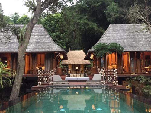 a villa with a swimming pool in front of a house at Four Seasons Tented Camp Golden Triangle in Golden Triangle