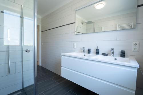 a white bathroom with a sink and a mirror at Moderne Ferienwohnung mit Ausblick in Bad Goisern