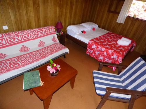 Cette chambre comprend deux lits, une table et une chaise. dans l'établissement Pension Temaeva, à Opoa