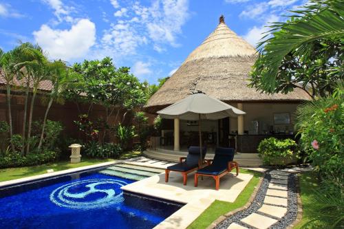 un complexe avec une piscine, 2 chaises et un parasol dans l'établissement The Dusun, à Seminyak
