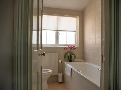 a bathroom with a tub and a toilet and a window at Phelips Arms in Yeovil