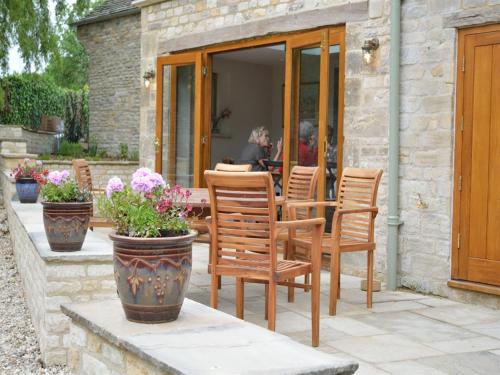 a patio with chairs and a table with flowers at The Plough B&B in Bourton on the Water