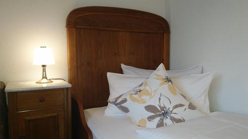 a bedroom with a bed with a wooden headboard and a lamp at Pension Landhaus Fischer in Maßweiler