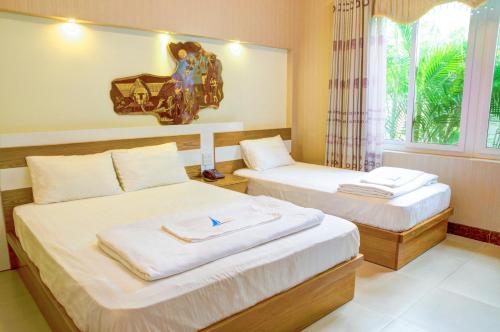 two beds in a room with a window at Mui Tau Hotel Phan Ri Cua in Tuy Phong