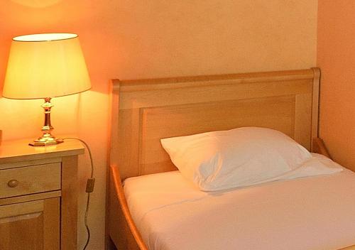 a bedroom with a bed with a lamp and a white pillow at Grand Hôtel des Rasses & Wellness in Les Rasses