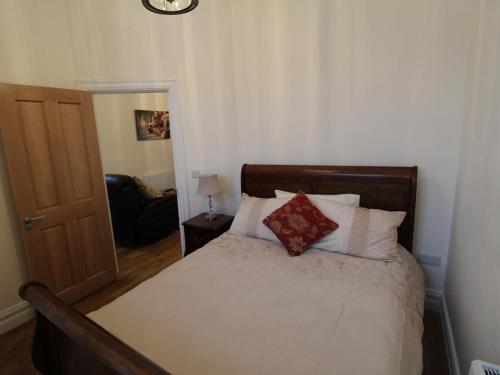 a bedroom with a bed with white sheets and red pillows at The Post House in Kinsale