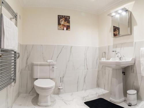 La salle de bains blanche est pourvue de toilettes et d'un lavabo. dans l'établissement The Post House, à Kinsale