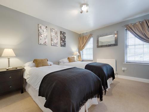 1 dormitorio con 2 camas y espejo en la pared en The Porterhouse, en Willingham