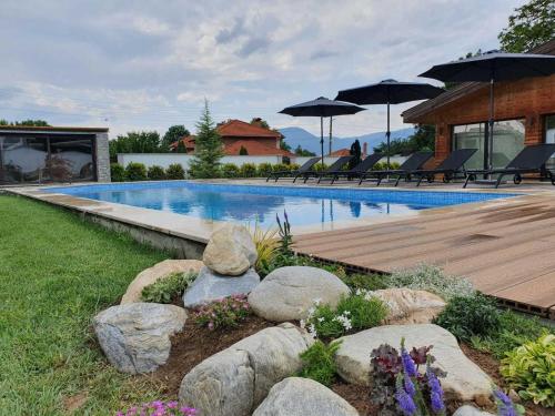 - une piscine avec des rochers et des parasols dans une cour dans l'établissement Vila Antik, à Garmen