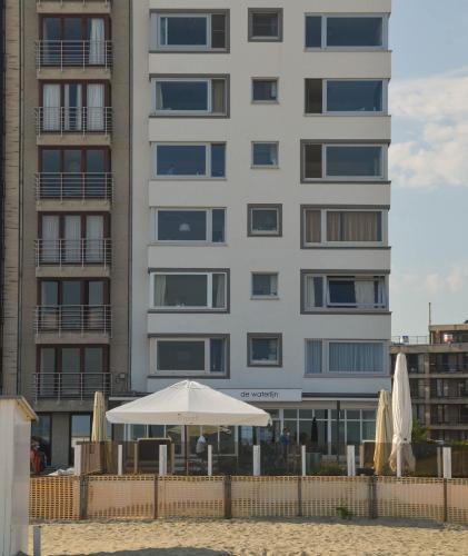 a building with an umbrella and umbrellas on the beach at appartement DE WATERLIJN in Knokke-Heist
