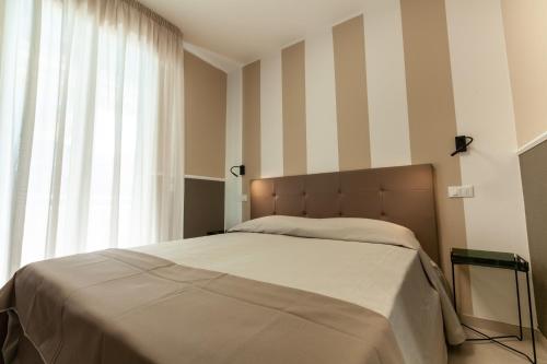 ein Schlafzimmer mit einem Bett mit gestreifter Wand in der Unterkunft Holiday Club Residence in Alba Adriatica