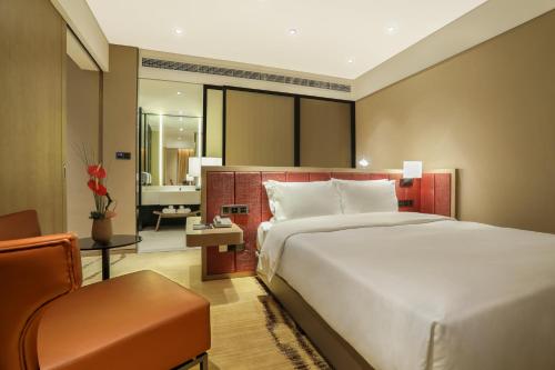 a hotel room with a large bed and a chair at Holiday Inn Express Chengdu Wenjiang Hotspring, an IHG Hotel in Chengdu