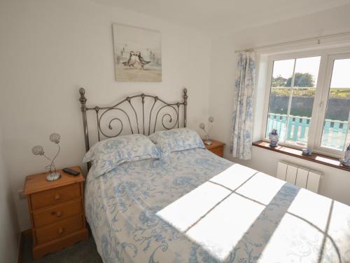 ein Schlafzimmer mit einem Bett und zwei Fenstern in der Unterkunft Ffrwd in Holyhead