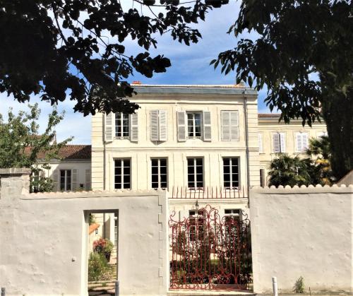 una casa blanca con una puerta y una valla en La Résidence des Indes, en La Rochelle