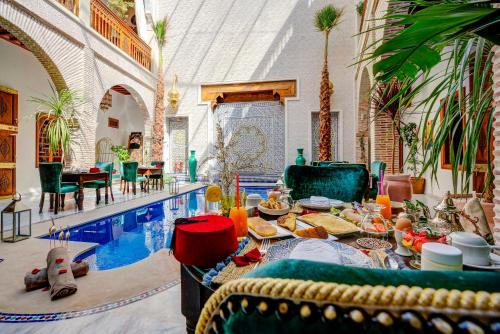 ein Wohnzimmer mit einem Tisch mit Essen neben einem Pool in der Unterkunft Riad Janate & SPA in Marrakesch
