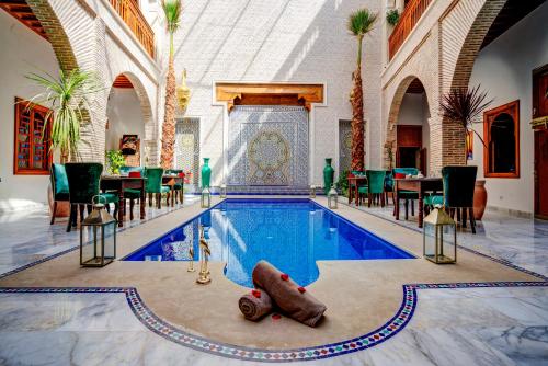 einen Pool in einem Gebäude mit einem Tisch und Stühlen in der Unterkunft Riad Janate & SPA in Marrakesch