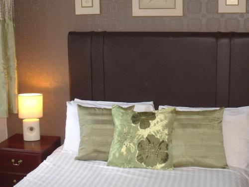 a bed with a black headboard and pillows and a lamp at Richmond Hotel in Weston-super-Mare