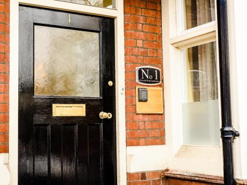 una porta nera con un cartello su un edificio di mattoni di 1 Riverside Apartments a Norwich