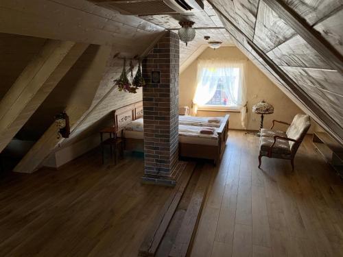 a attic room with a bed and a window at Arbatinės apartamentai in Biržai