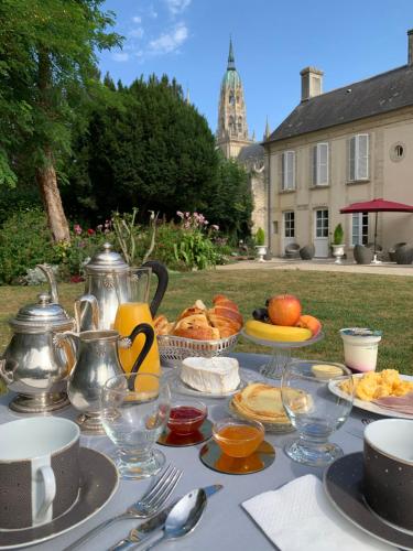 a table with plates of food and pitchers of orange juice at Le Tardif, Noble Guesthouse in Bayeux