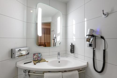 a white bathroom with a sink and a mirror at ibis Luebeck City in Lübeck
