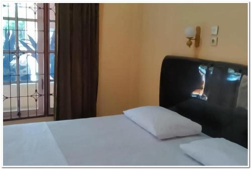 1 dormitorio con cama blanca y ventana en Hotel Maharani Syariah Mitra RedDoorz, en Pematangsiantar