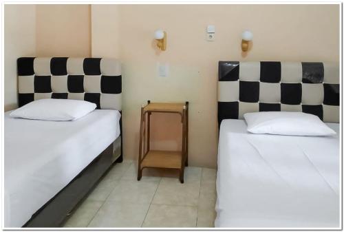 2 camas en una habitación con rayas blancas y negras en Hotel Maharani Syariah Mitra RedDoorz, en Pematangsiantar