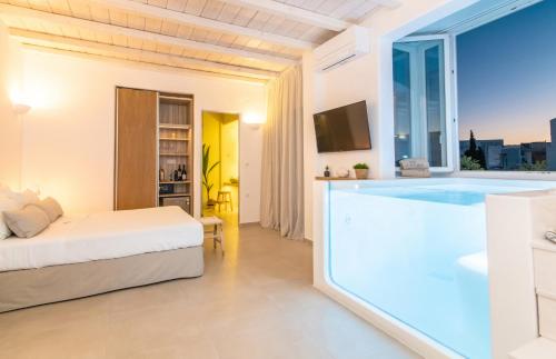 una camera con una grande vasca da bagno e un letto di Vincenzo Family Rooms a Città di Tinos