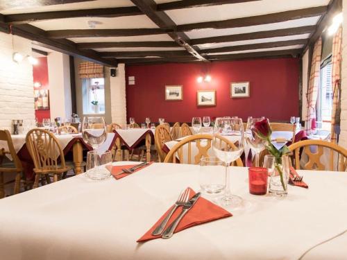 uma sala de jantar com mesas e cadeiras com toalha de mesa branca em The Rose and Crown em Thorpe le Soken