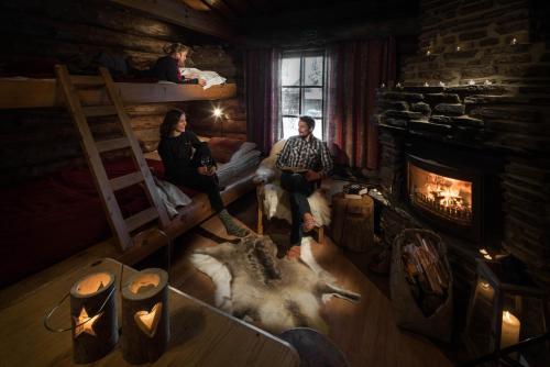 a group of people sitting in a room with a fireplace at Lapland Hotels Luostotunturi & Amethyst Spa in Luosto
